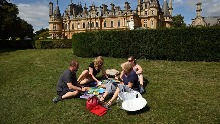 Visitors enjoying a picnic on the lawn on a sunny day at Waddesdon Manor, Buckinghamshire
